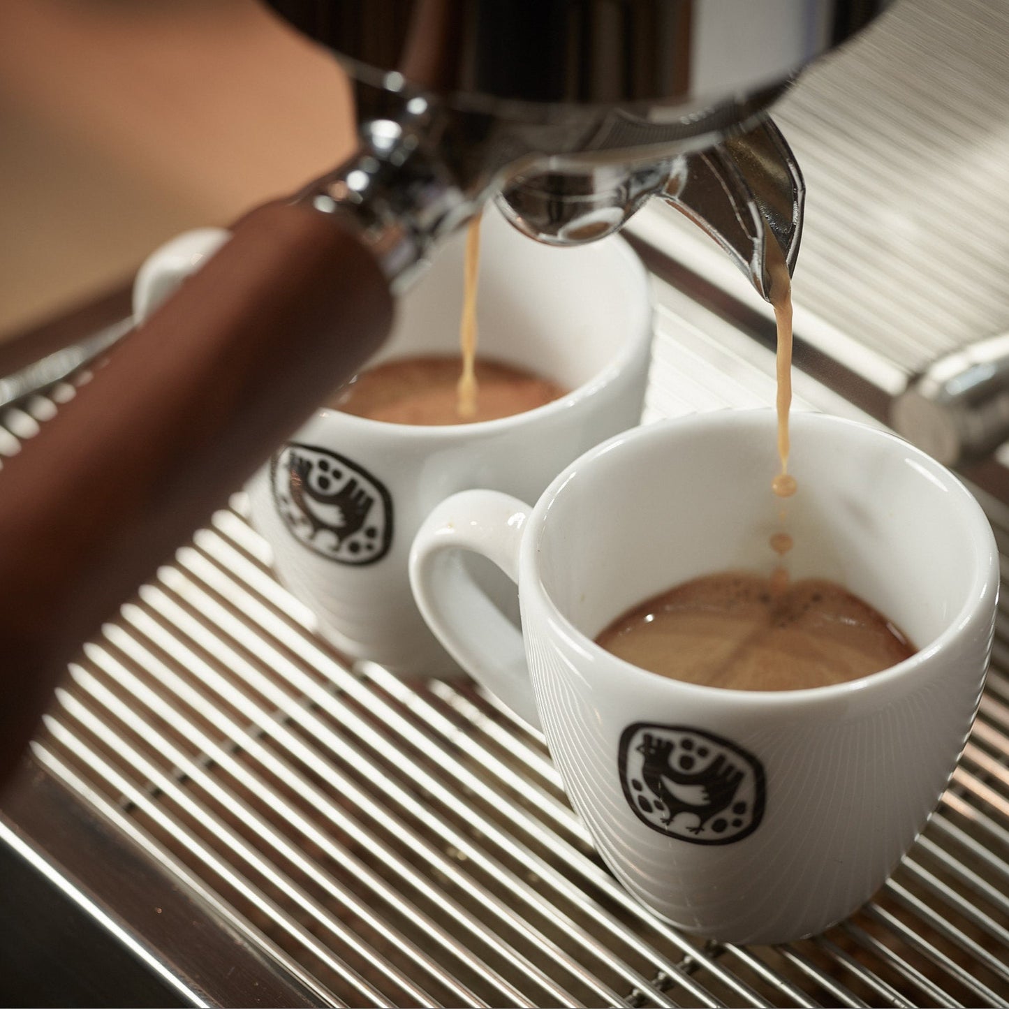 Espresso pouring into two cups in a barista seminar for advanced coffee techniques.
