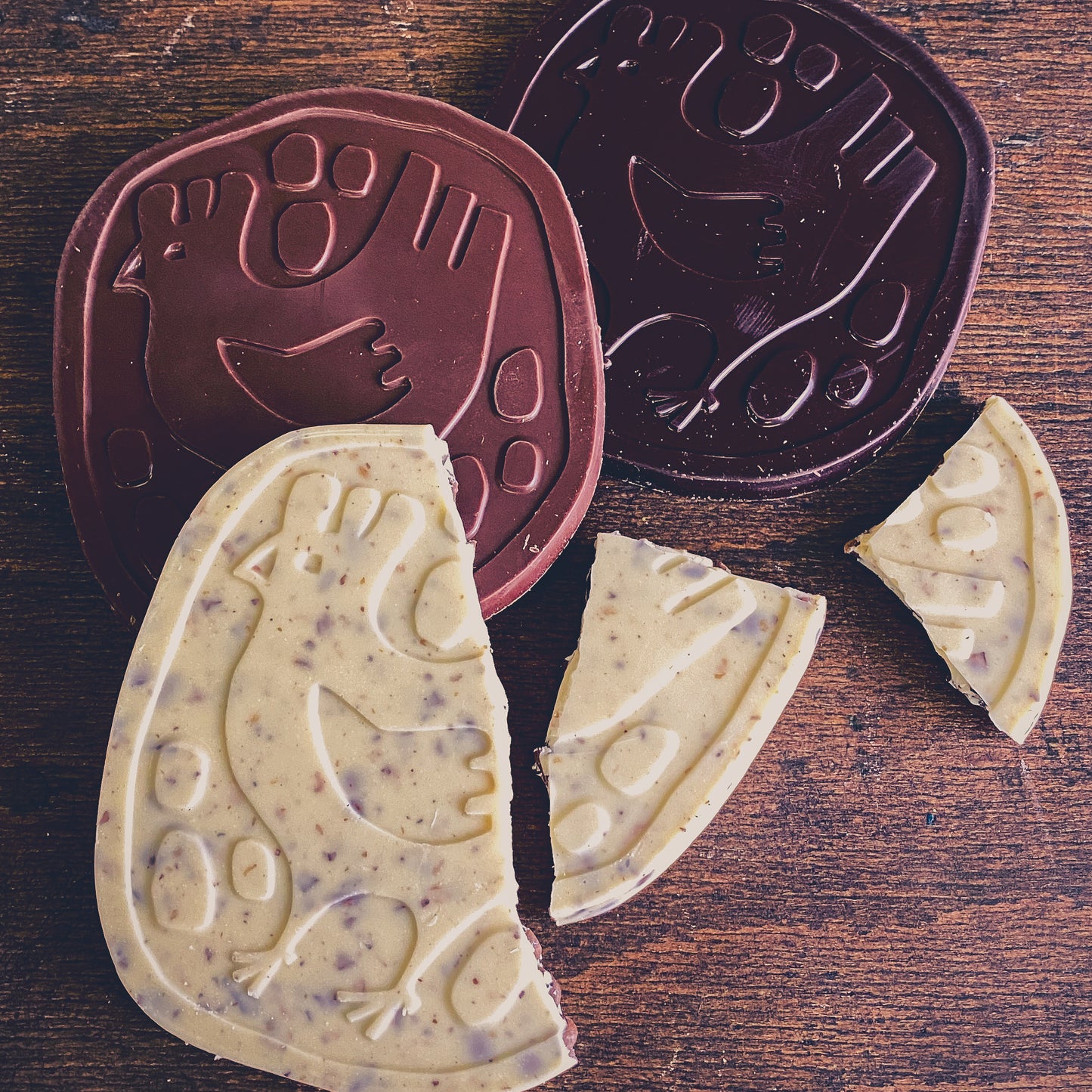 Erlebnis-Paket Schokolade featuring broken chocolate bars with chicken designs in dark and milk varieties.